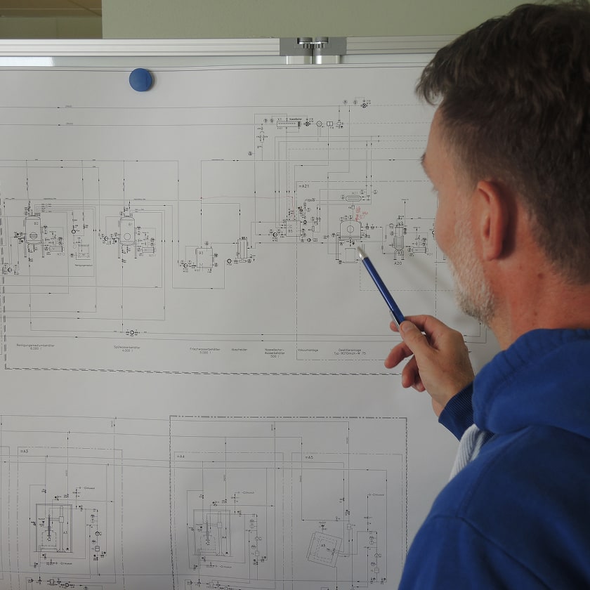Ein Konstrukteur bei Renzmann vor den Plänen einer ROTOmaX Destillieranlage