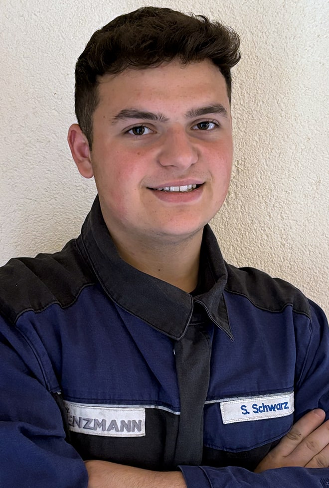 Junger Mann in blauer Arbeitskleidung lächelt