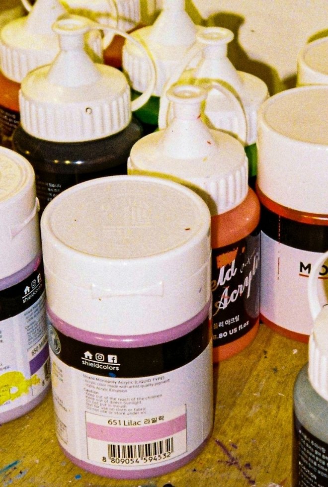 Mehrere Acrylfarbenflaschen auf einem Holztisch